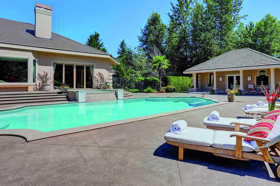 Casa con impresionante piscina pavimentada con hormigón estampado.